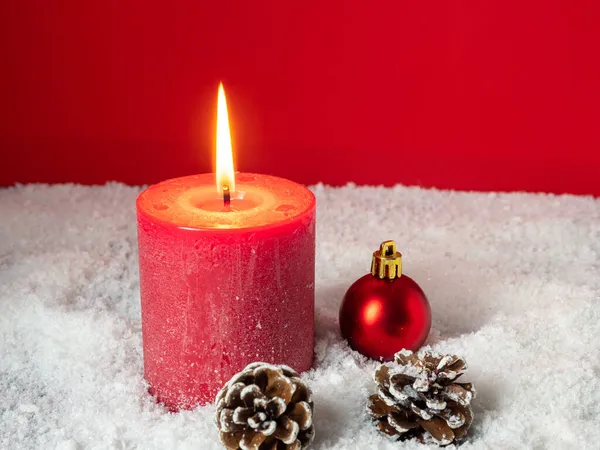 Красная рождественская свеча и рождественские украшения на красном фоне. — стоковое фото