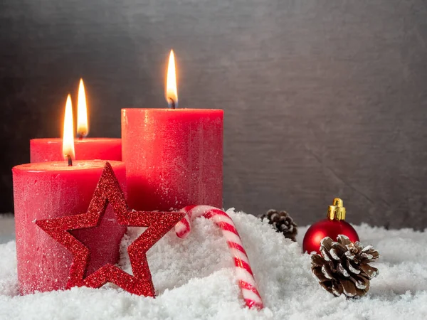 Candela di Natale rossa e decorazioni natalizie su sfondo grigio. Foto Stock Royalty Free