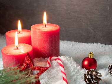 Kırmızı Noel mumu ve gri arka planda Noel süslemeleri.