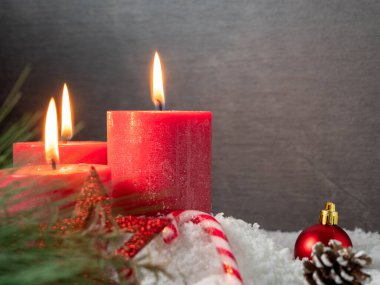 Kırmızı Noel mumu ve gri arka planda Noel süslemeleri.