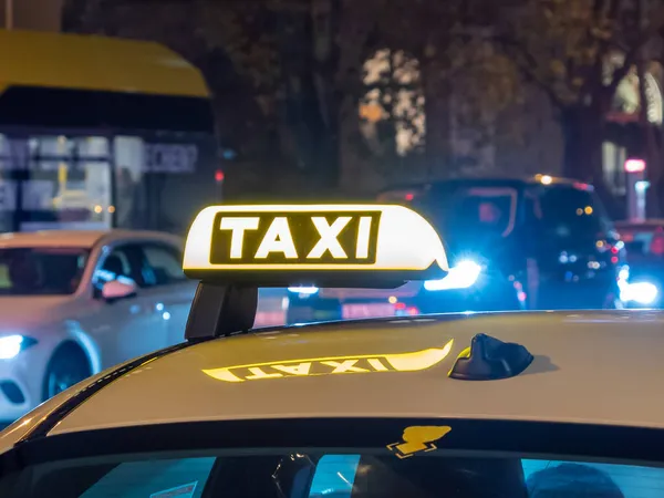 Photographie nocturne d'une voiture de taxi. Panneau de taxi sur le toit de la voiture brille dans le dar — Photo