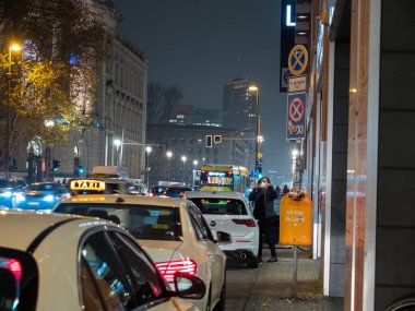 Bir taksi arabasının gece fotoğrafı. Arabanın çatısındaki taksi tabelası darda parlıyor.