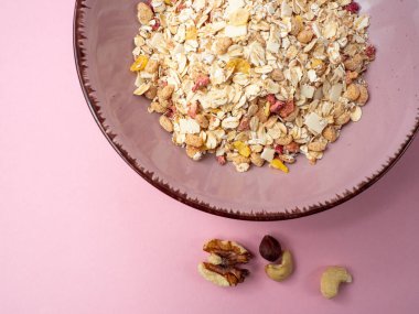 Muesli in a pink cup on a pink table. Muesli on a pink background.