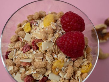 Muesli in a glass glass and berries on a pink table. Muesli on a pink background.