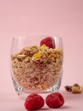 Muesli in a glass glass and berries on a pink table. Muesli on a pink background.