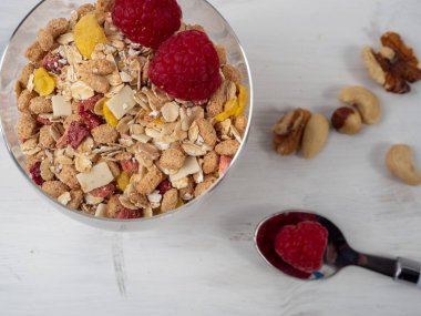Muesli in a glass glass and berries on a white table. Muesli on a wooden white background.