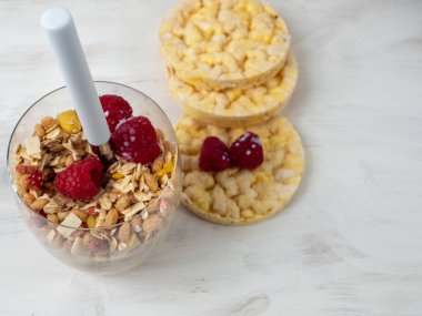 Muesli in a glass glass and berries on a white table. Muesli on a wooden white background.