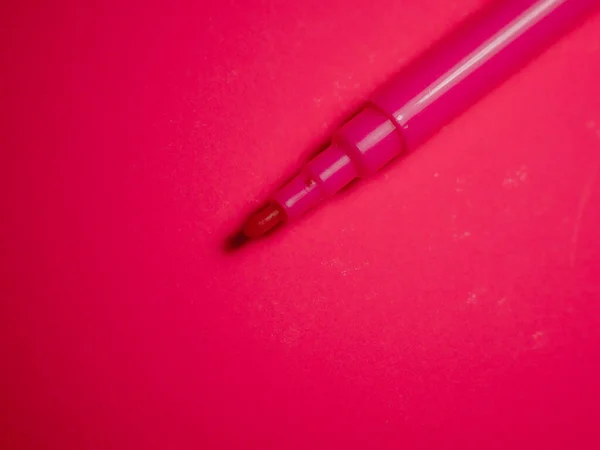 Red felt-tip pen on red background. Colored felt-tip pen.