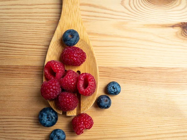 Ahşap bir arka planda ahududu ve yaban mersini. Taze ahududu ve yabanmersini..