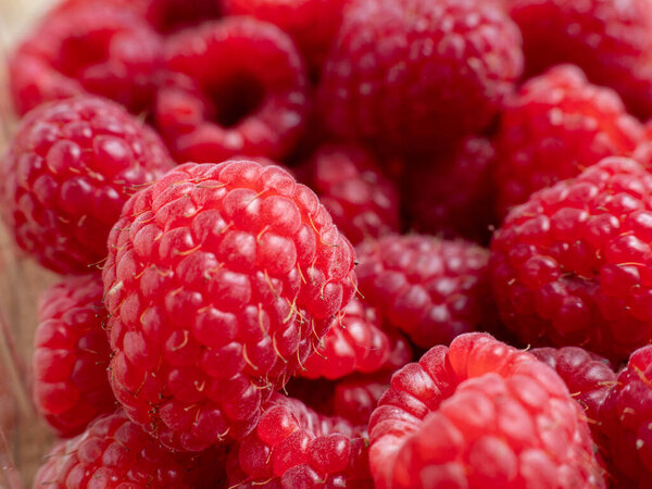 Raspberries in a wooden bowl. Raspberries on a wooden background.