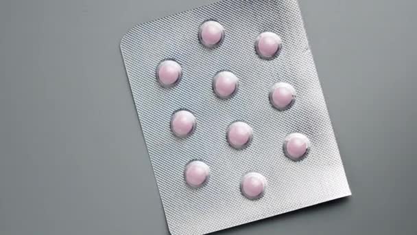 Rózsaszín tabletták egy szürke háttér. — Stock videók