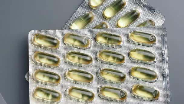 Jasně žluté lesklé Omega-3 pilulky ovinout kolem na šedém pozadí. — Stock video