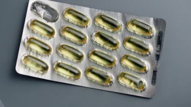 Parlak sarı, parlak Omega-3 hapları gri bir arka plana sarılmış.. 