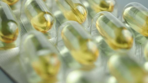 Brillante giallo lucido Omega-3 pillole avvolgere su uno sfondo grigio. — Video Stock