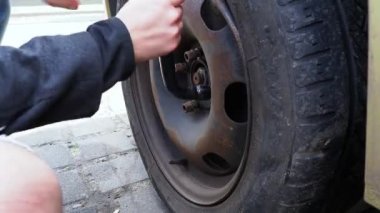 Araba tekerleği değiştirme. Anahtar arabanın ön tekerleğini söküyor..