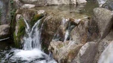 Su kayaların üzerinden akar. Taşların arasında akın.