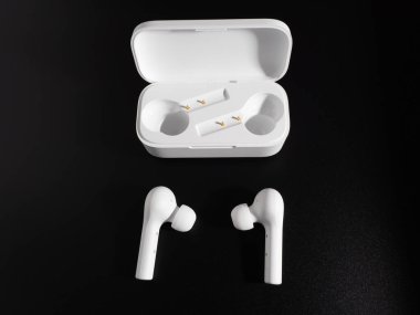 Siyah arka planda beyaz kablosuz kulaklık.