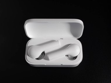 Siyah arka planda beyaz kablosuz kulaklık.