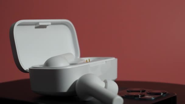 Λευκά Ασύρματα Ακουστικά Και Τηλέφωνο Ροζ Φόντο — Αρχείο Βίντεο