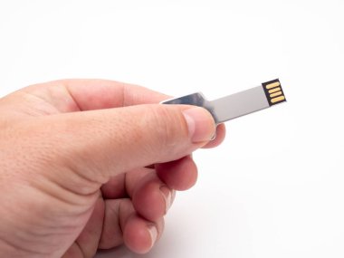 Bir el, arka planda gümüş bir USB belleği anahtar şeklinde tutar..