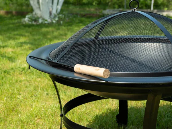 Yeşil otların arka planında ateş için metal kase. Kapaklı metal ateş kasesi..