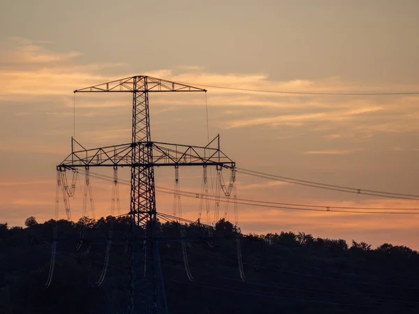 Pillars of high-voltage wires at sunset