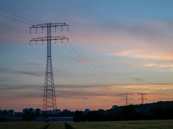 Pillars of high-voltage wires at sunset