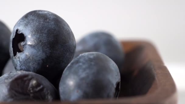 Blueberry dalam cangkir kayu dengan latar belakang putih. blueberry close-up. — Stok Video