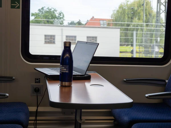 Laptop on the table in the train. Laptop and bottle on the table in the train car on the table.