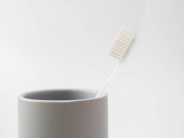 Toothbrushes in a glass with copy space on a white background.