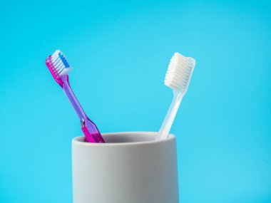 Mavi arkaplanda kopyalama alanı olan bir bardaktaki diş fırçaları.