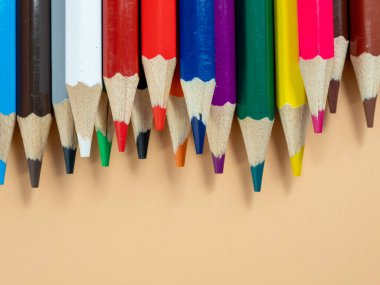 Eğitim ve okul konseptine geri dönüş. Turuncu arka planda renkli kalemler.