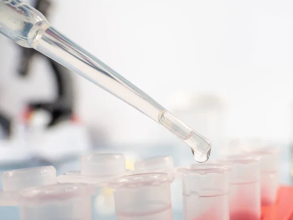 Analytical chemistry - sample being pipetted into test tube for analysis in laboratory.