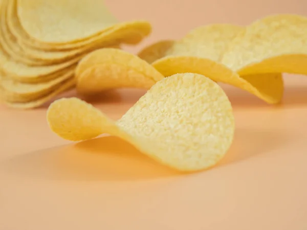 Crisps. Crispy potatoes. Potato chips on an orange background. Close-up.