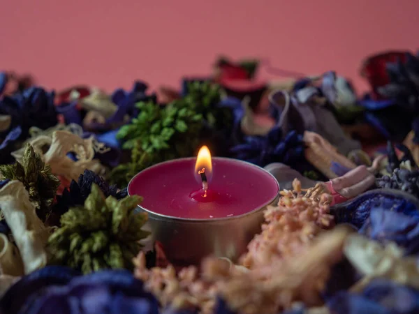 Candle among flower confetti or potpourri. Burning candle and flower confetti. Candle close-up.