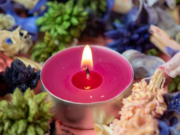 Candle among flower confetti or potpourri. Burning candle and flower confetti. Candle close-up.