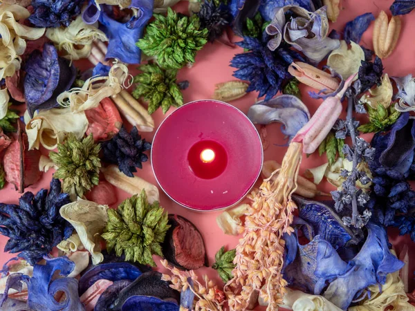 Candle among flower confetti or potpourri. Burning candle and flower confetti. Candle close-up.