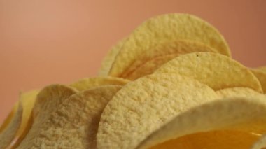 Fried potato chips rotating on an orange background. Crispy chips. High quality 4k footage