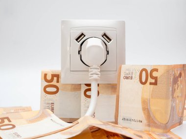 Çevresinde bir prizi ve avro banknotları olan bir elektrik prizi. Elektrik maliyeti ve pahalı enerji kavramı