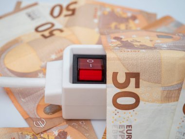 Etrafında elektrik prizi ve euro banknotları var. Elektrik maliyeti ve pahalı enerji kavramı