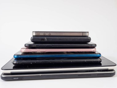 Eski akıllı telefonlar birbirinin üzerine yatar. Bir yığın eski cep telefonu. Beyaz arkaplanda akıllı telefonlar.