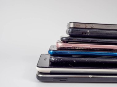 Eski akıllı telefonlar birbirinin üzerine yatar. Bir yığın eski cep telefonu. Beyaz arkaplanda akıllı telefonlar.