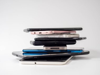 Eski akıllı telefonlar birbirinin üzerine yatar. Bir yığın eski cep telefonu. Beyaz arkaplanda akıllı telefonlar.
