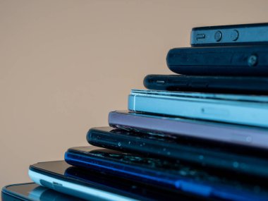 Eski akıllı telefonlar birbirinin üzerine yatar. Bir yığın eski cep telefonu. Turuncu arka planda akıllı telefonlar.