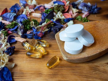 Tablets and capsules in a wooden spoon. Multivitamins and supplements from natural concept.