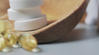 Tablets and capsules in a wooden spoon. Multivitamins and supplements natural product concept.