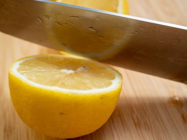 Sliced lemons with a knife. Ripe lemon on a wooden board. Fresh lemons on a wooden background.