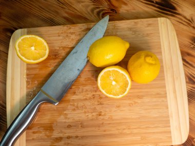 Sliced lemons with a knife. Ripe lemon on a wooden board. Fresh lemons on a wooden background.