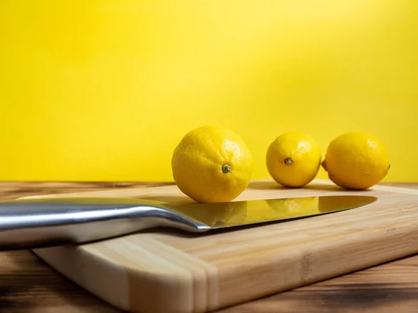 Cut fruit with a knife. Ripe oranges and a knife on a wooden board. Fresh oranges on a wooden background.