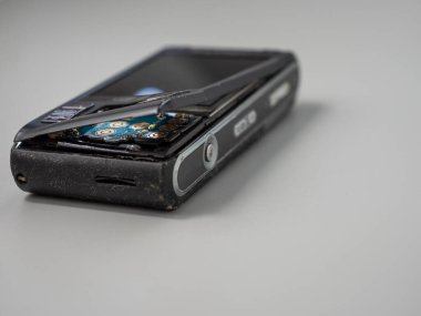 Old push button mobile phone. Broken phone. Phone on a gray background.